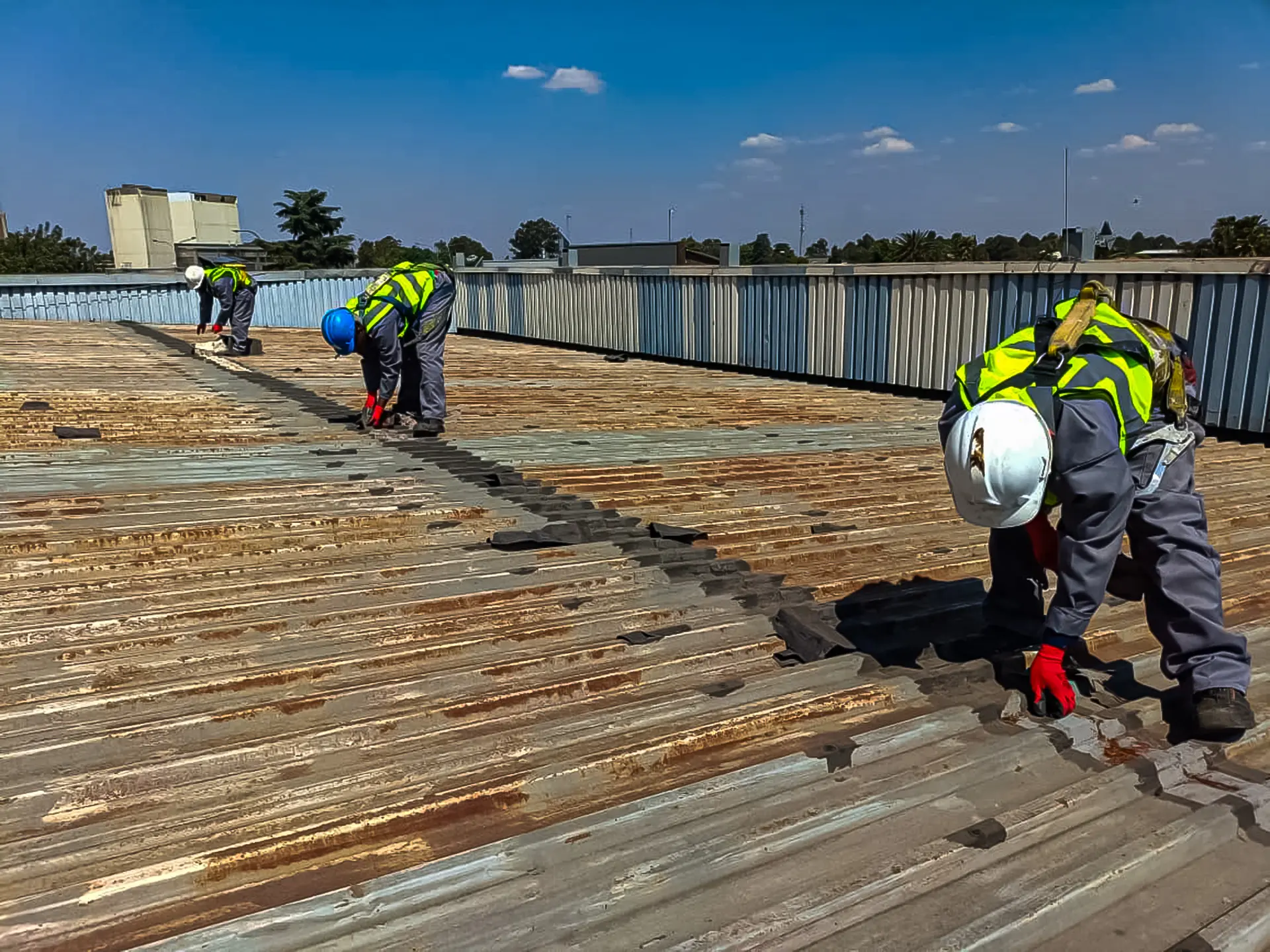Skilled technicians perform crucial commercial roof leak repair on a large, weathered industrial building, restoring structural integrity now.