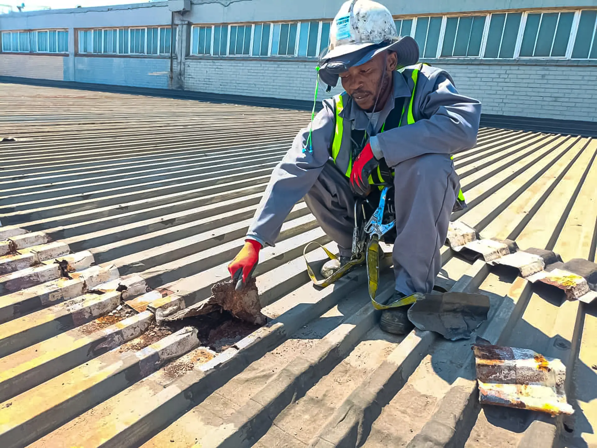 Skilled worker in safety gear performs vital industrial leak repair on a corroded metal roof, ensuring structural integrity.